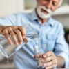 Älterer Mann gießt Wasser in das Glas