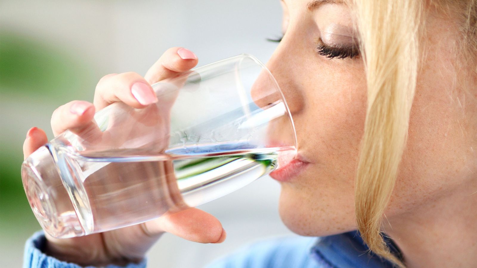 Frau trinkt basisches Wasser aus einem Glas