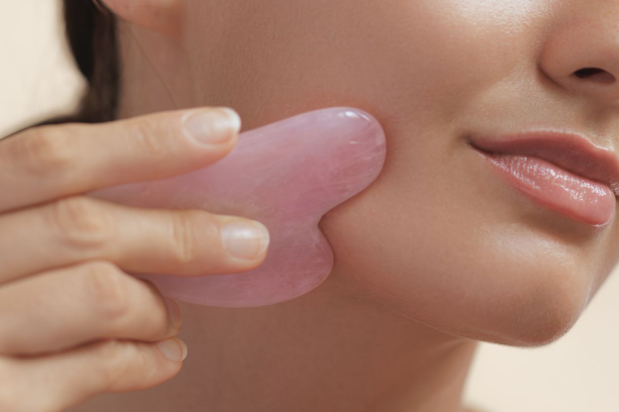 Konzept für Schönheit und Hautpflege für Frauen mit Gua Sha-Werkzeug zur Selbstmassage des Gesichts