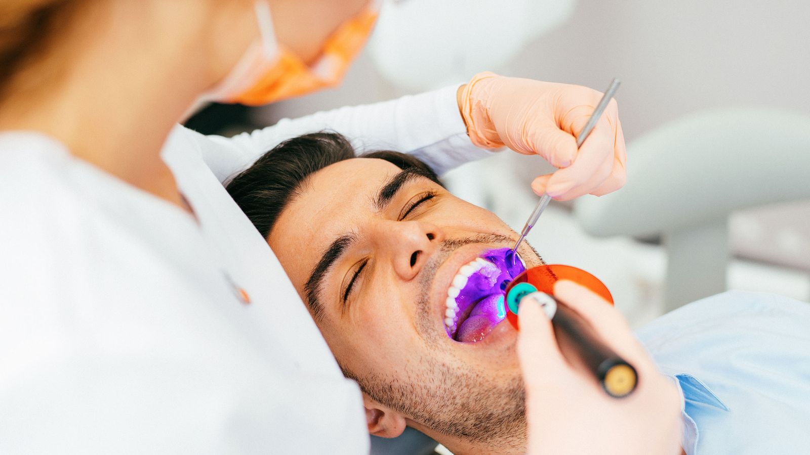Zahnärztin macht eine komposite Zahnfüllung bei einem Patienten