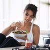 Frau isst Salat in der Küche