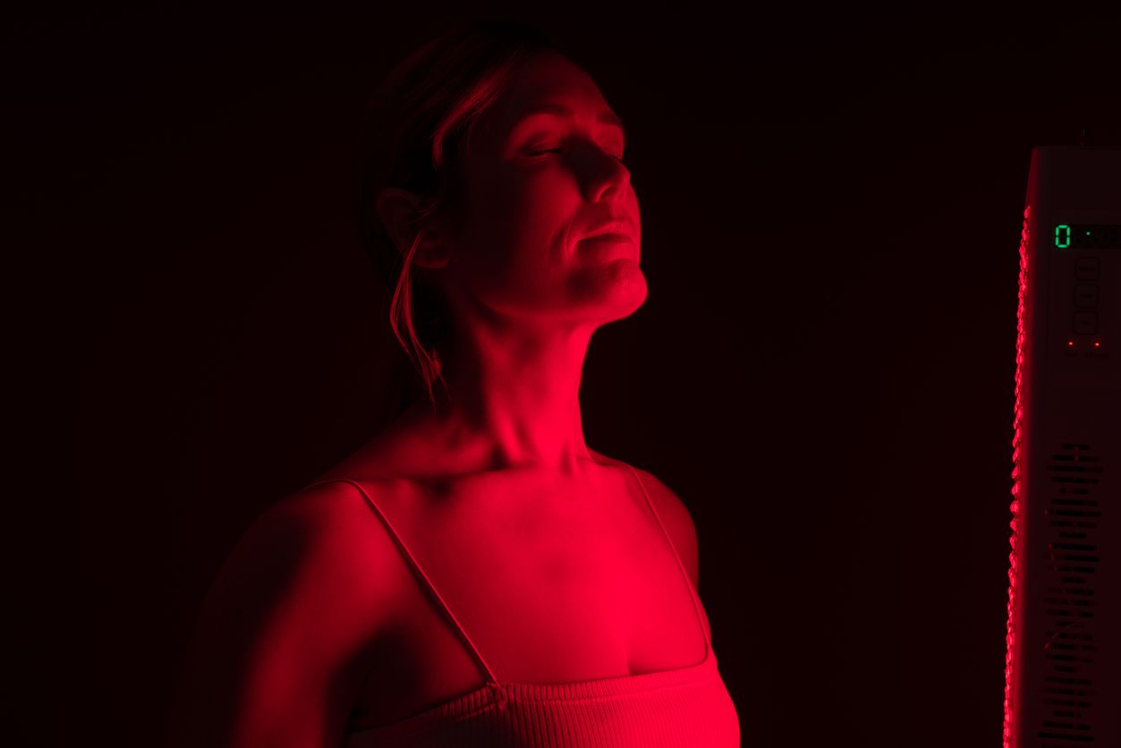 Frau erhält Rotlichttherapie von einem Rotlichtgerät