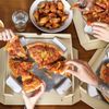 Fastfood: Pizza, Chicken Wings und Tortilla-Chips auf einem Tisch