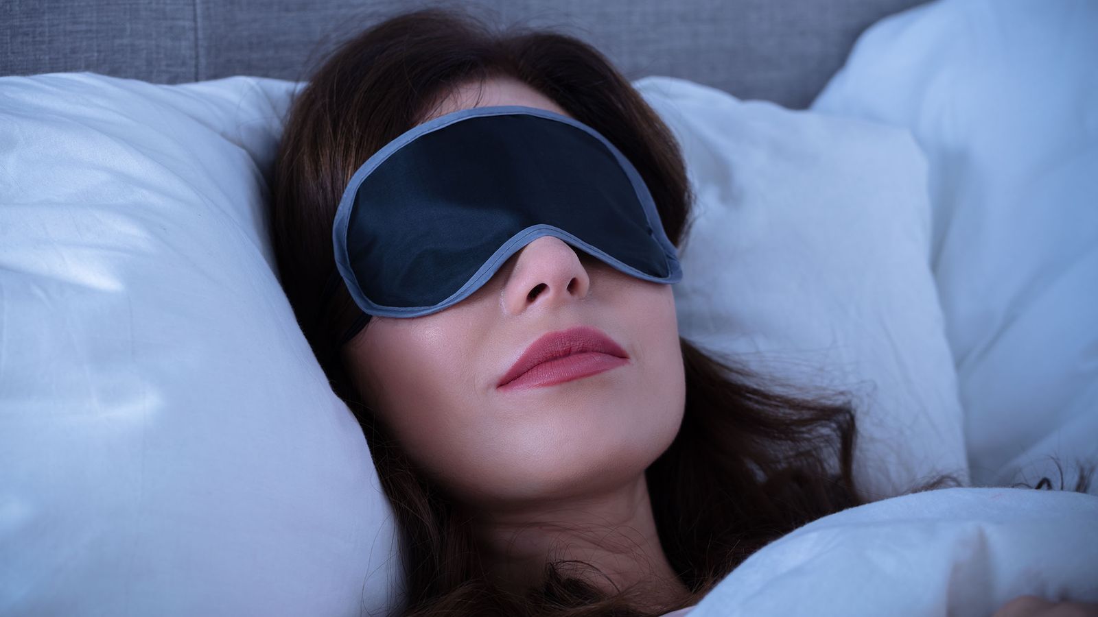 Frau schläft im dunkeln mit Augenmaske