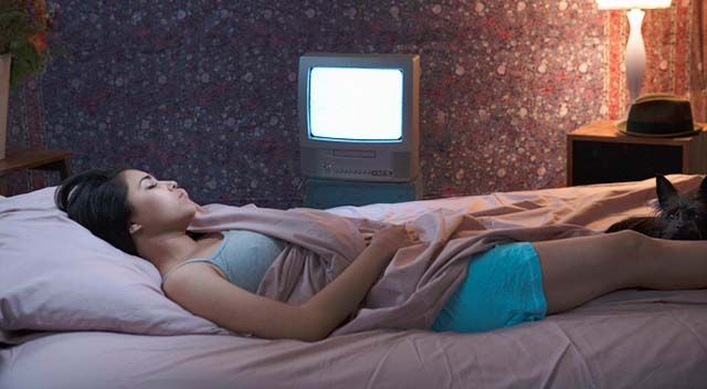 Frau schläft mit laufendem Fernseher im Hintergrund