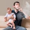 Vater mit Baby auf dem Arm raucht