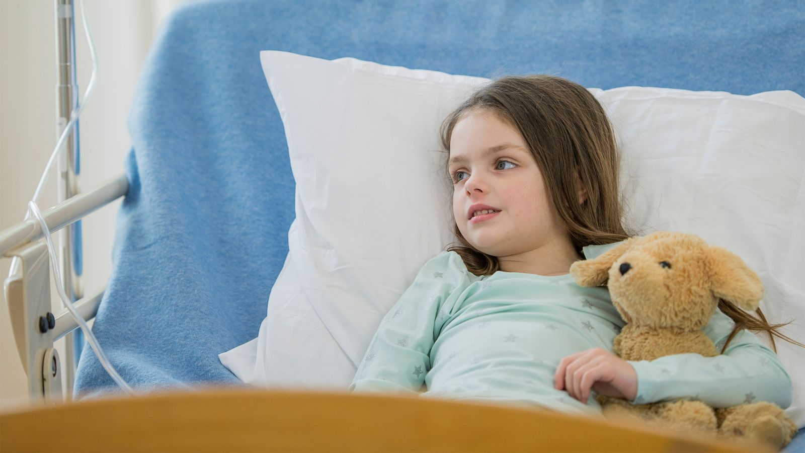 Kind ist im Krankenhaus und hält einen Teddy