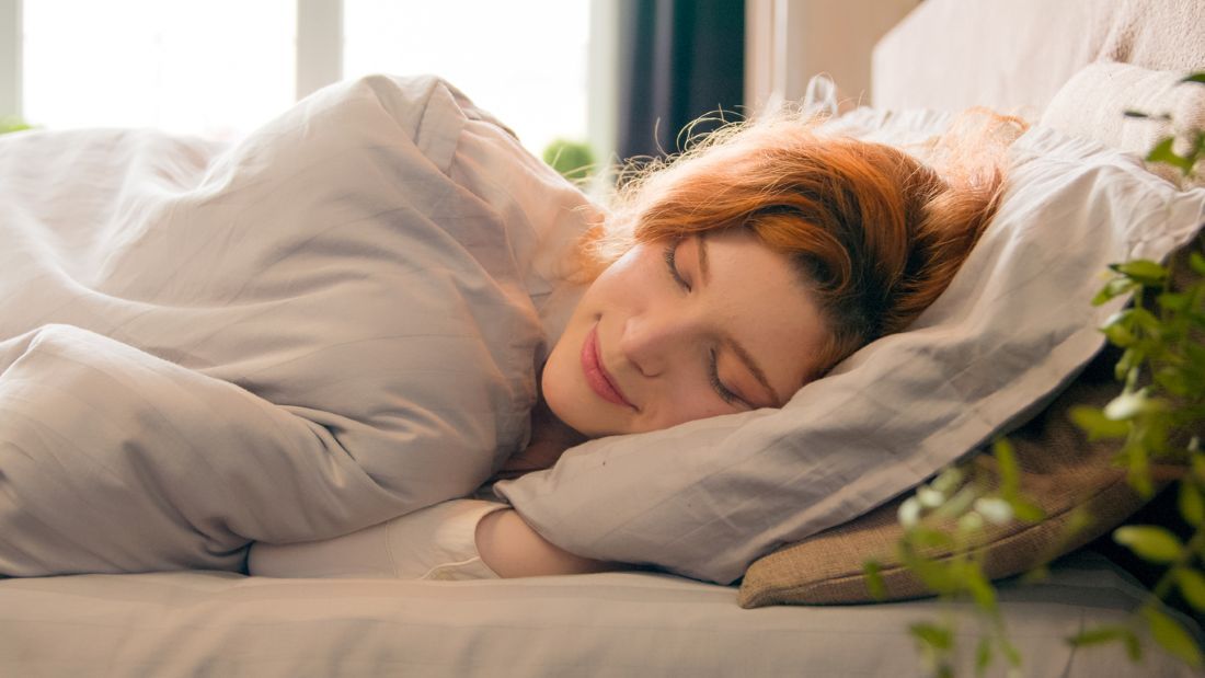 Glückliche Frau, die zu Hause in einem bequemen gemütlichen Bett schläf