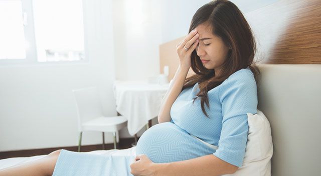 Schwangere Frau hat Kopfschmerzen wegen niedrigem Blutdruck