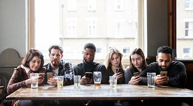 6 Freunde sitzen am Tisch und alle schauen aufs Handy