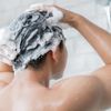 Person wäscht sich Haar mit Shampoo, welches Giftstoffe enthält