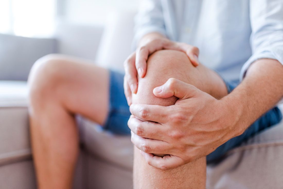 Ein Mann massiert seine schmerzhafte Knie