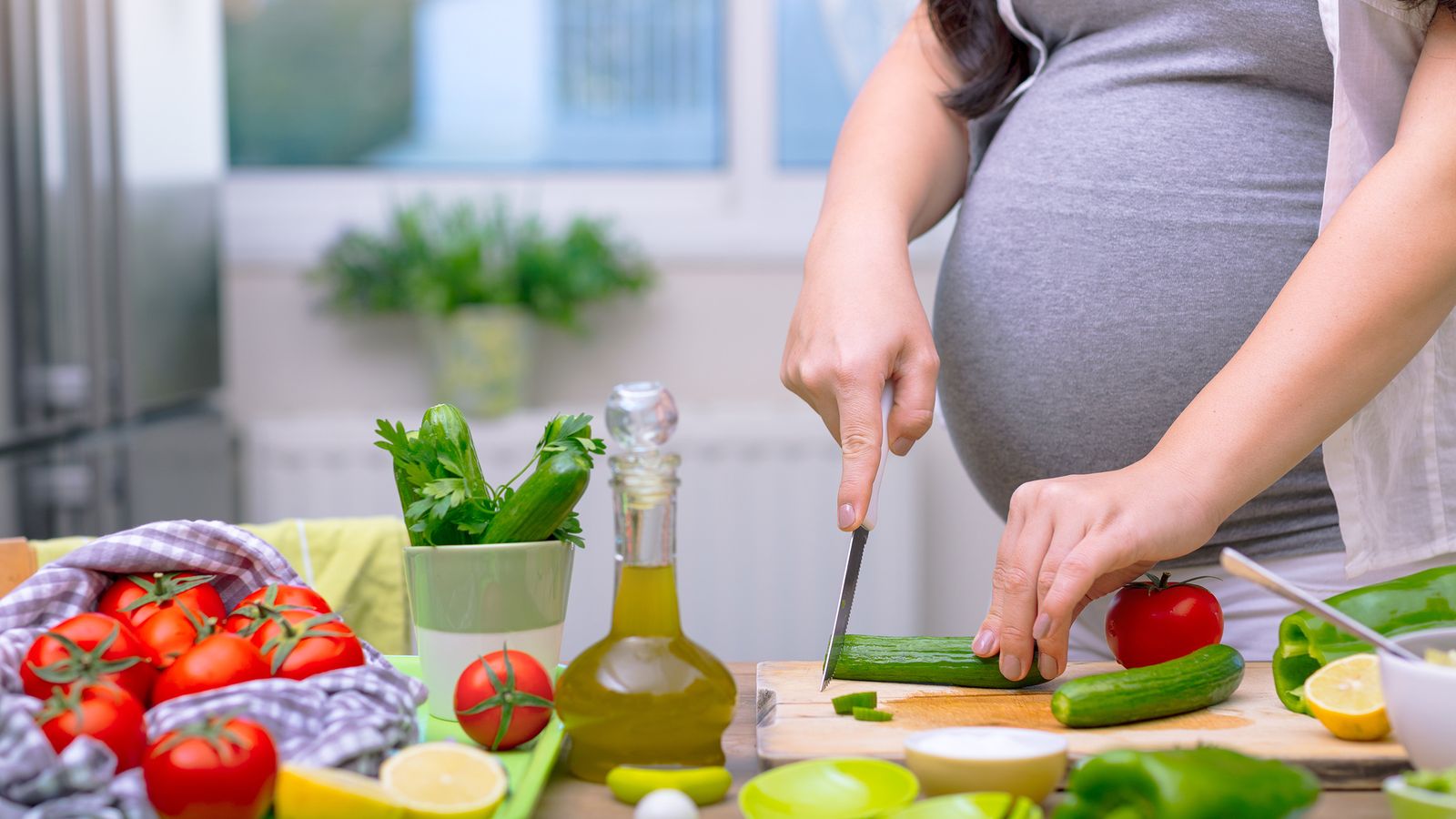 Schwangere Frau schneidet frisches Gemüse