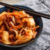 Selbst gemachtes Kimchi aus Chinakohl, Karotte und Apfel in einer dunkelblauen Schüssel serviert