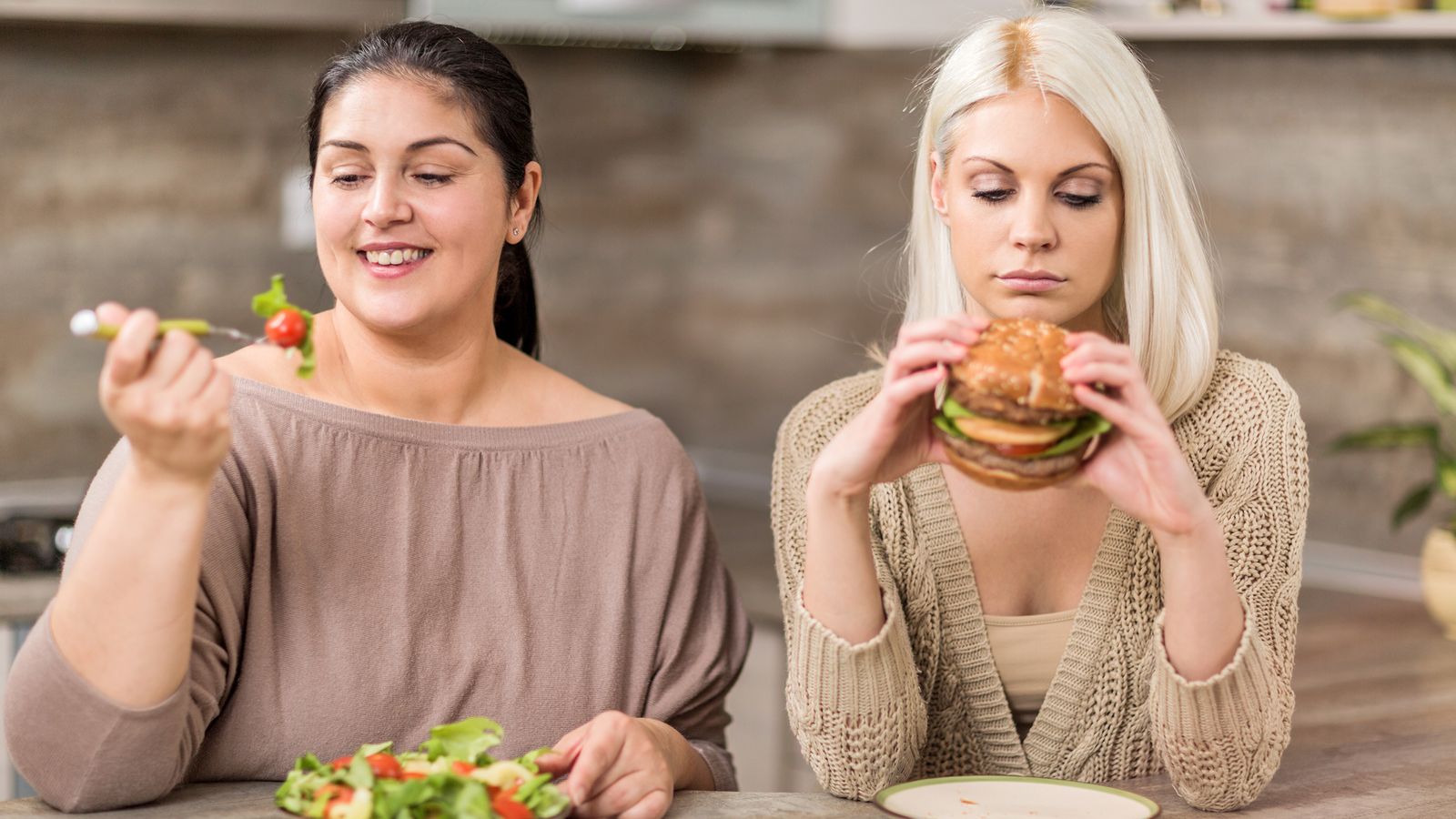 Zwei Frauen, eine isst gesund, die andere isst Fastfood