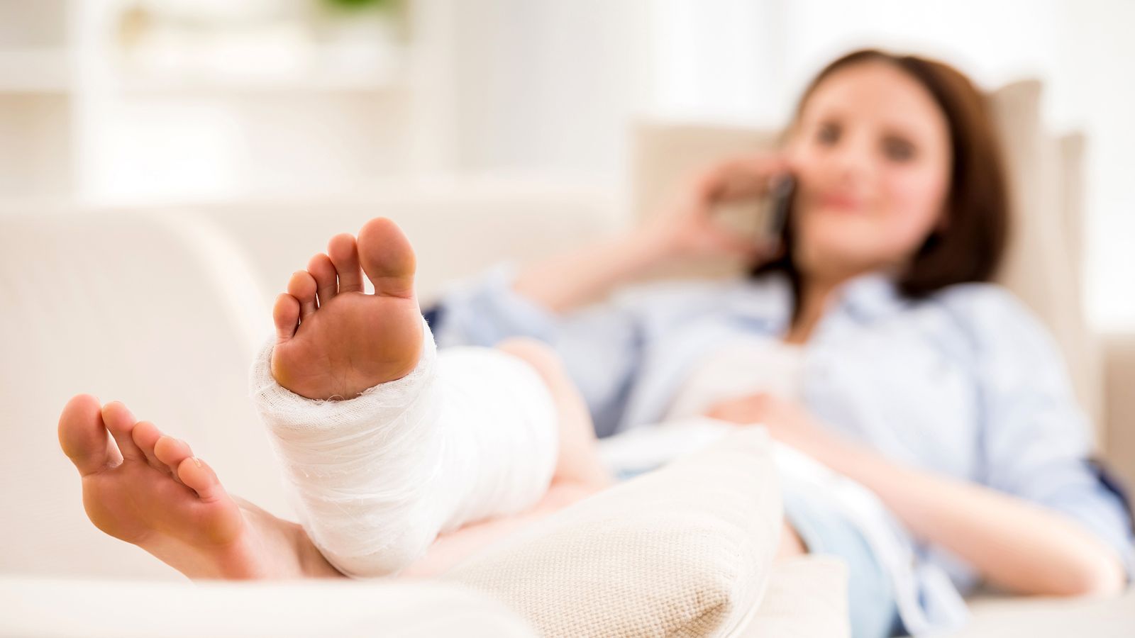 Frau liegt mit gebrochenem Bein auf einem Krankenbett
