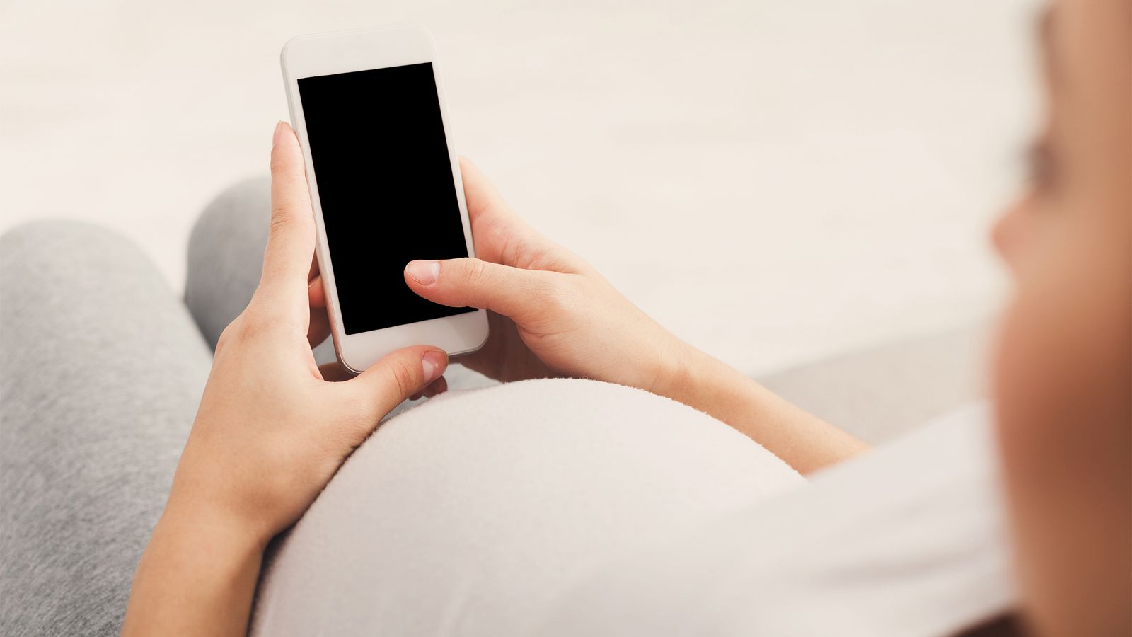 Frau isst am Handy während sie schwanger ist