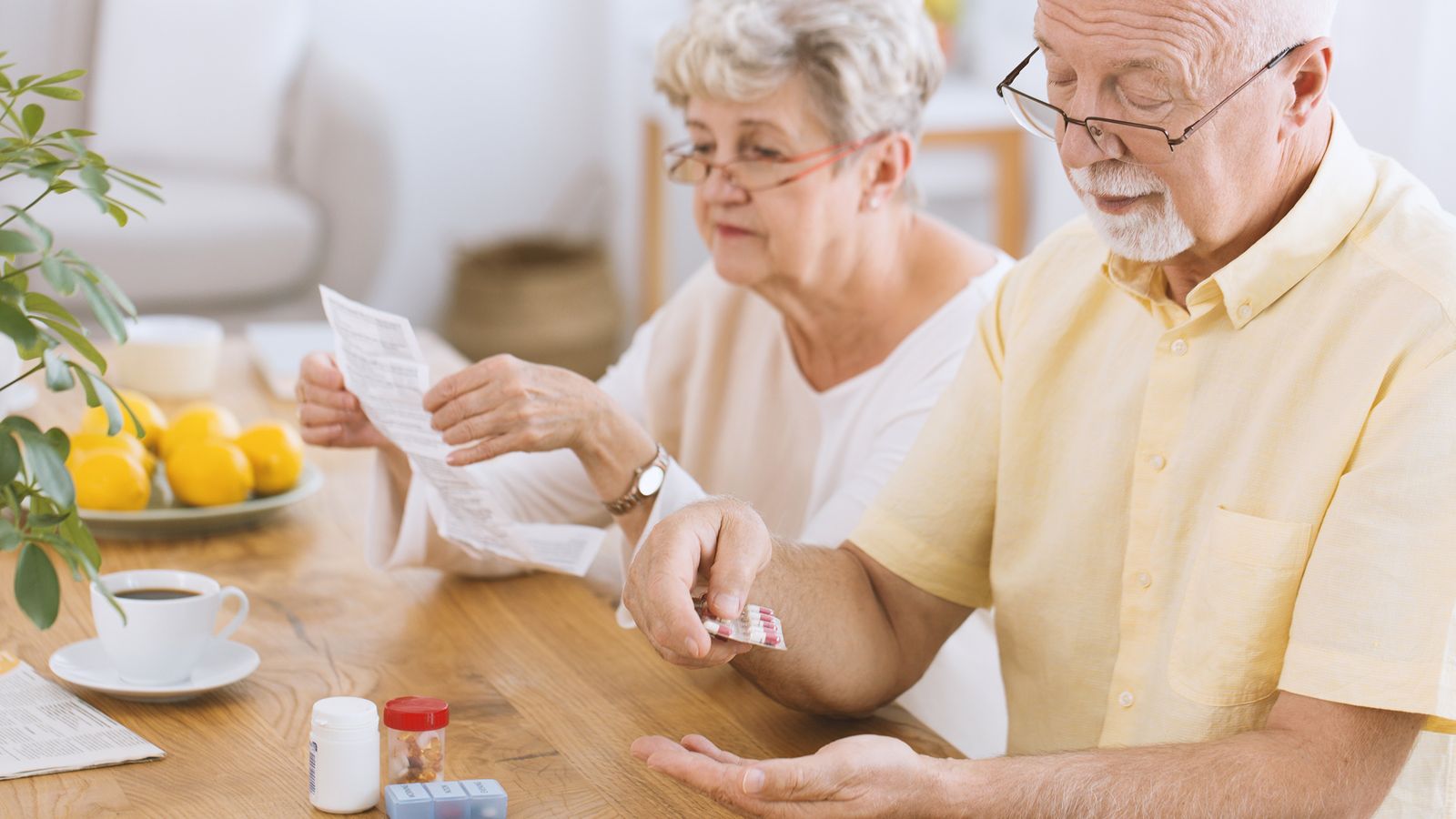 Ehepaar sitzt am Tisch und nimmt Medikamente gegen einen hohen Cholesterinspiegel ein
