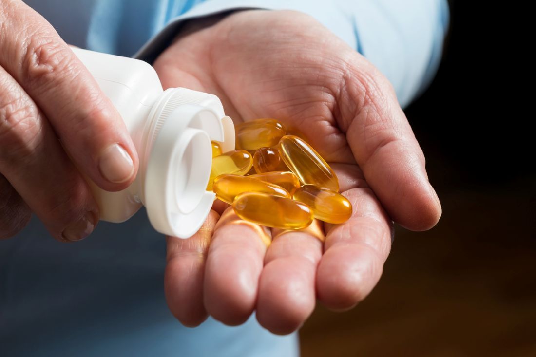 Frau Hand hält gelbe Medikamente Kapseln Omega-3