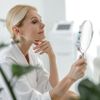Gut aussehende Frau betracht sich im Spiegel