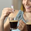 Frau trinkt Kaffee und nimmt Süssstoff