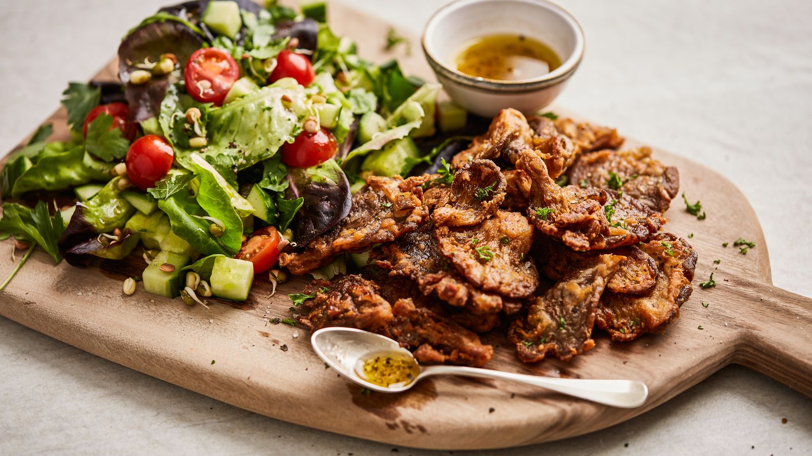 Gebratene Austernpilze und Salat auf einem Brett