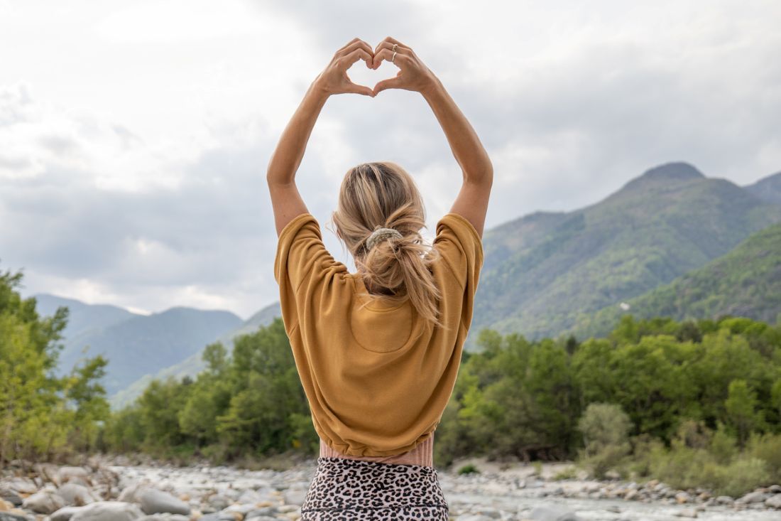 Junge Frau liebt die Natur, sie macht Herz mit Händen 