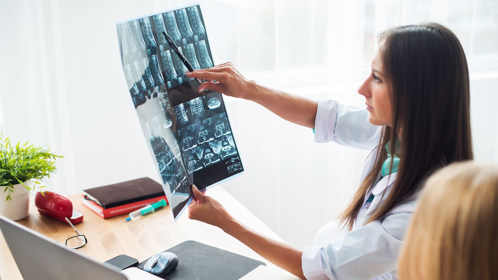 Ärztin und Patienten betrachten Röntgen-Aufnahmen