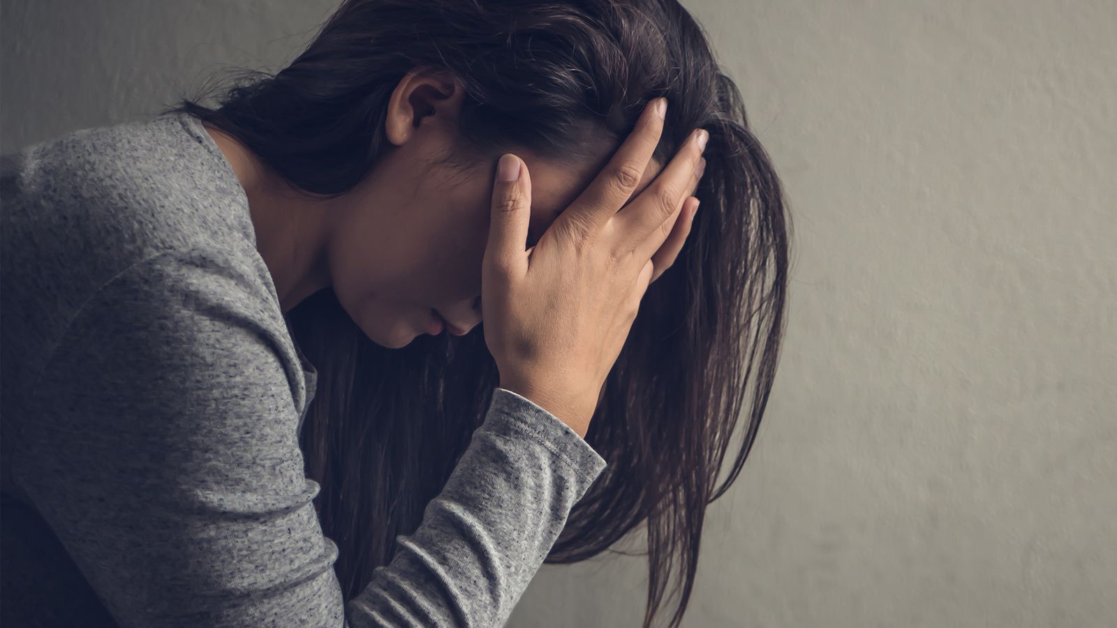Eine Frau mit dem polyzystischen Ovarialsyndrom sitzt depressiv am Boden