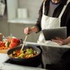 Frau kocht frisches Gemüse mit digitalem Tablet für Rezept