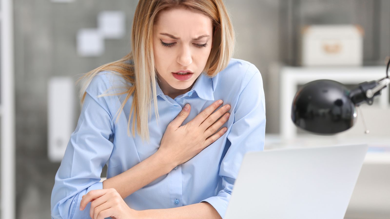 Frau mit Schmerzen in der Brust im Büro