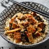 Tofu Sichuan auf Basmatireis serviert in einer schwarz-weiss karierten Schüssel mit Stäbchen