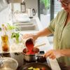 Frau in der Küche, die Tomatensauce zubereitet