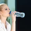 Junge Frau trinkt aus einer Plastik-Wasserflasche