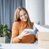 Junge Frau, die ein Paket öffnet, das sie online bestellt hat