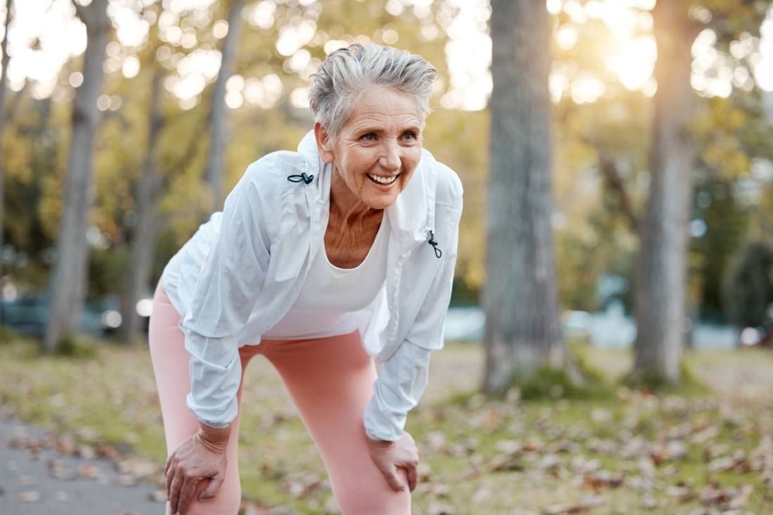 Müde, glückliche und ältere Frau, die im Outdoor-Naturpark für den Ruhestand Gesundheit, Wellness und Fitness-Training läuft