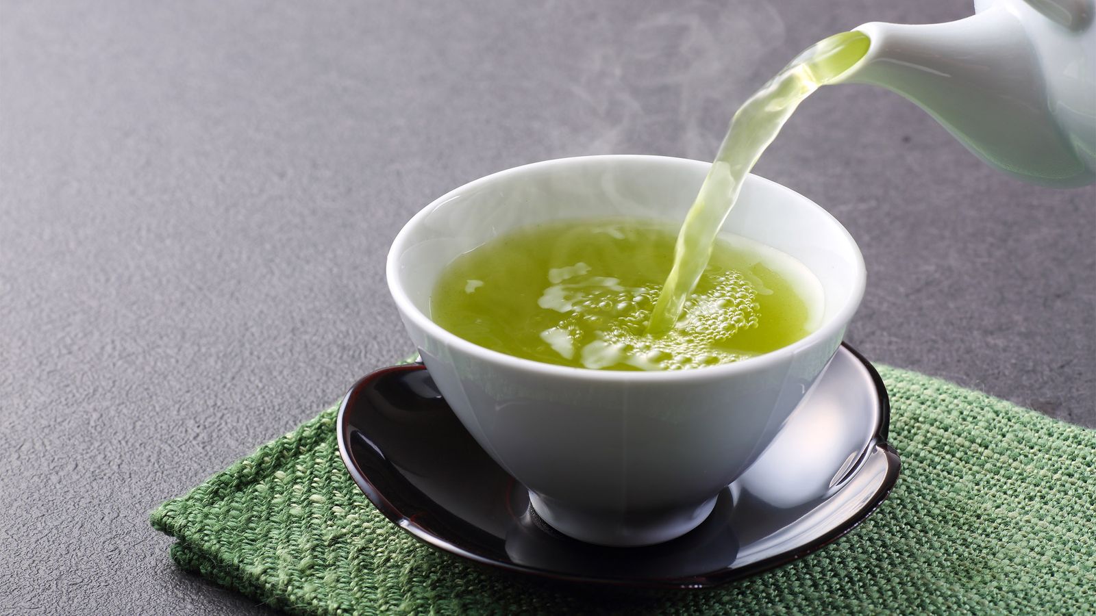 Grüner Tee wird in eine Tasse gegossen