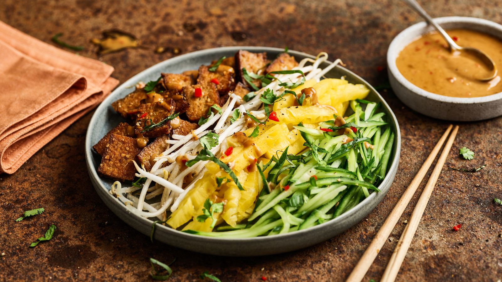 Knuspriger Tofu an knackigem Salat mit Erdnusssauce auf einem Teller serviert
