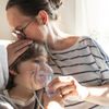 Krankes Kind mit Mutter inhaliert mit Vernebler zu Hause im Bett mit einer Lungenentzündung