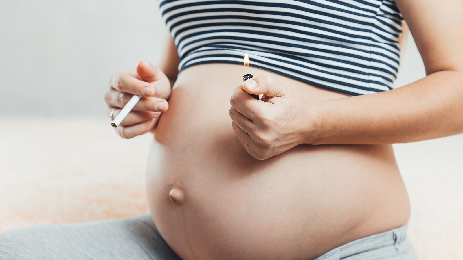 Schwangere Frau hält Zigarette in der Hand