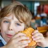 Ein Kind isst ungesunder Burger