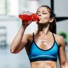 Junge sportliche Frau trinkt nach dem Training im Fitnessstudio einen Softdrink aus einer Plastikflasche
