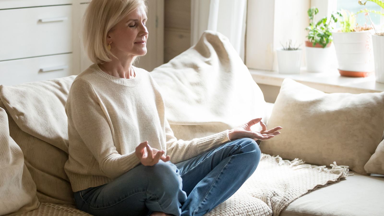 Frau meditiert auf ihrem Sofa
