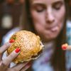 Frau isst einen Burger und ist süchtig