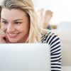 Frau liegt vor dem Laptop und ist zufrieden mit dem Fernstudium