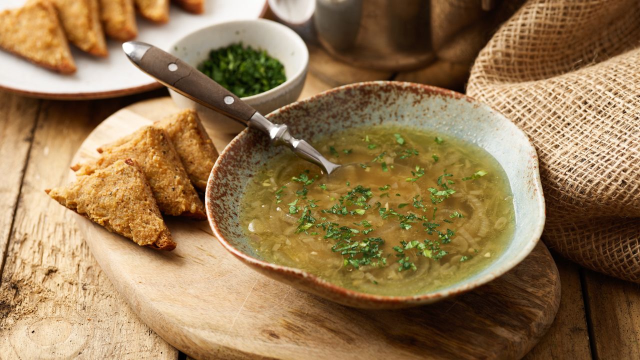 Zwiebelsuppe auf einem Holzbrett mit Crostinis