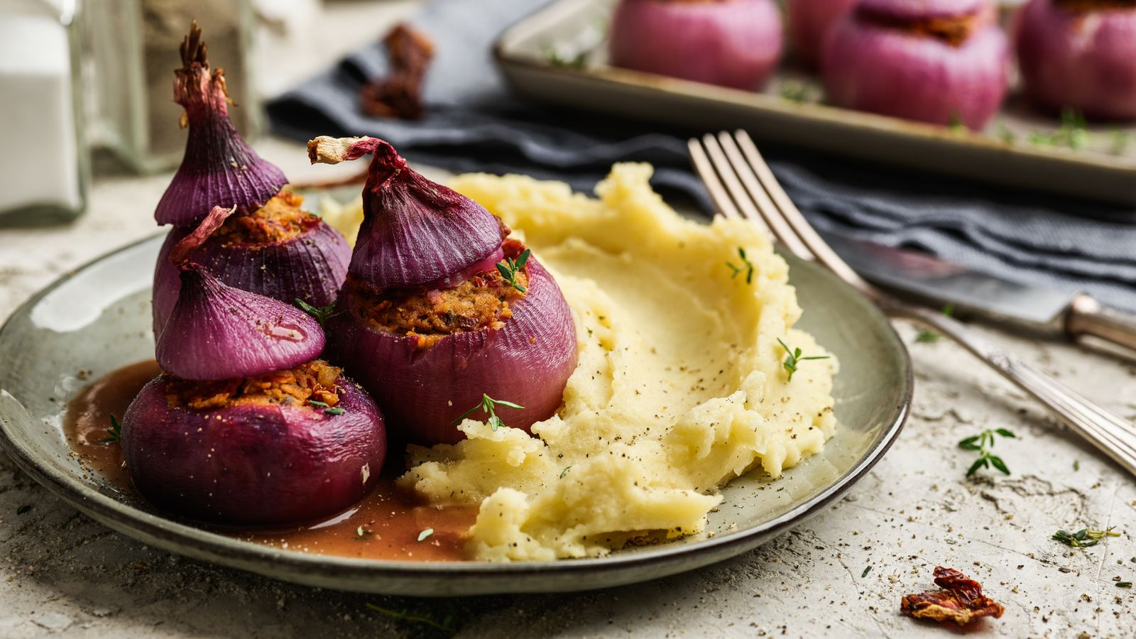 Gefüllte Zwiebeln an Rotweinsauce mit Kartoffelpüree auf einem Teller