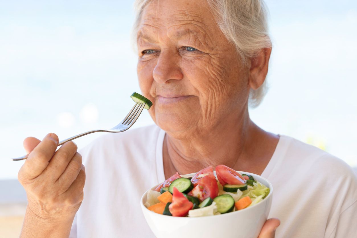 àltere Dame isst einen Salat