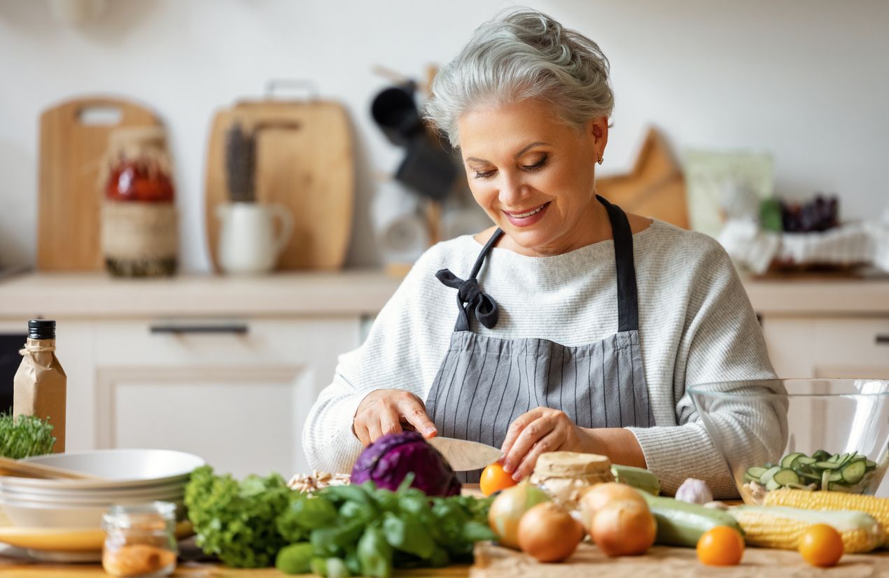 Glückliche reife Frau bereitet gesunden Salat in der Küche