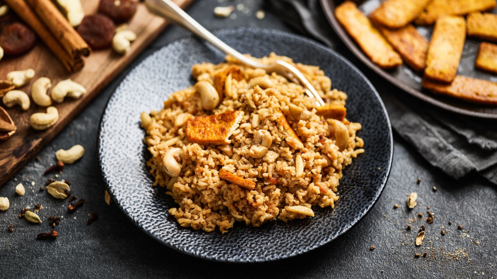 Gewürzreis mit Tofu auf einem dunklen Teller serviert